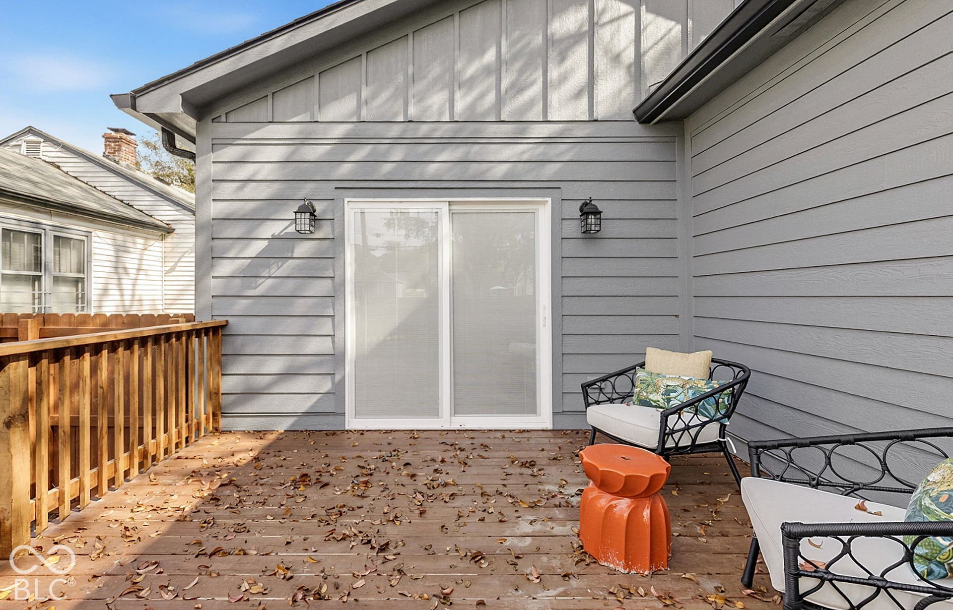 Exterior deck featuring wood-finish flooring, a wood perimeter railing, horizontal lap siding, and dual wall-mounted outdoor light fixtures