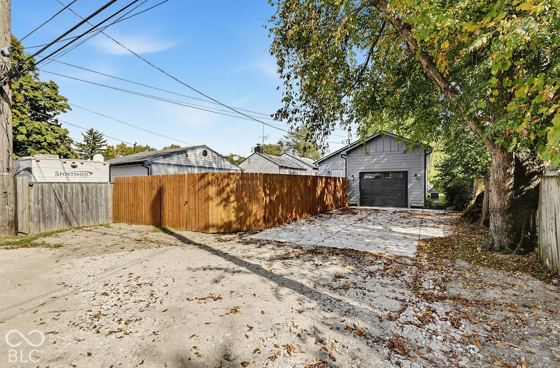 Detached garage with charcoal-colored siding and a matching garage door, concrete apron, and wood privacy fencing