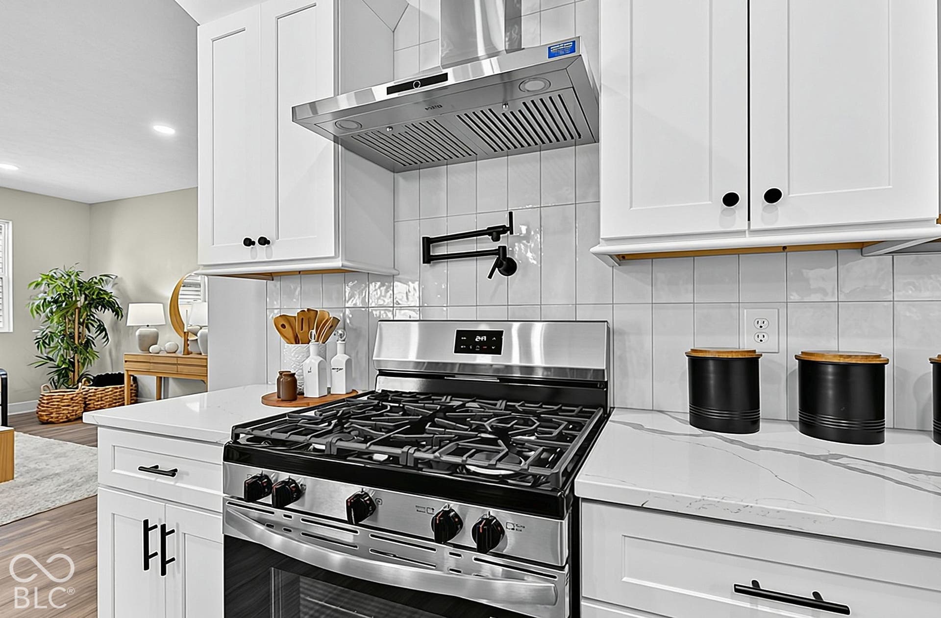 Kitchen featuring white shaker-style cabinetry, quartz countertops with gray veining, a stainless steel gas range, a stainless steel range hood, and a wall-mounted pot filler faucet