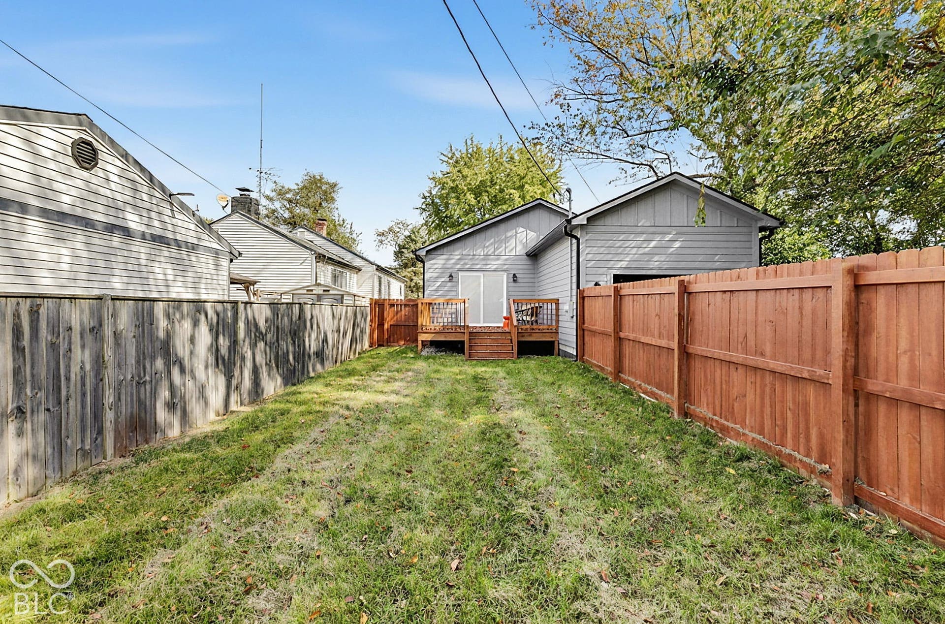 Private backyard featuring a wooden deck, sliding glass doors, and enclosed by wood privacy fencing