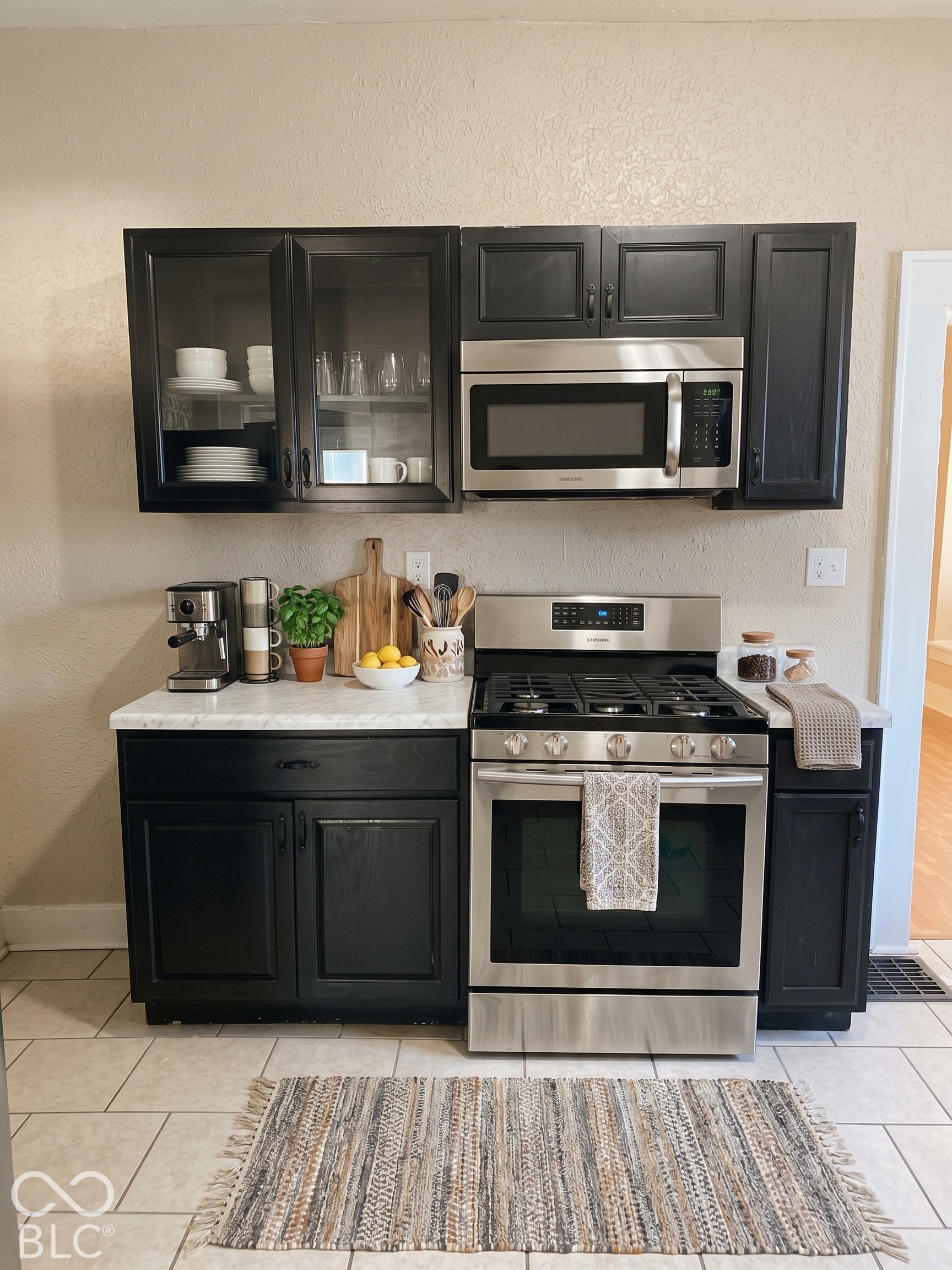 Virtually Altered - Kitchen featuring glass cabinet door, SS gas stove and microwave.