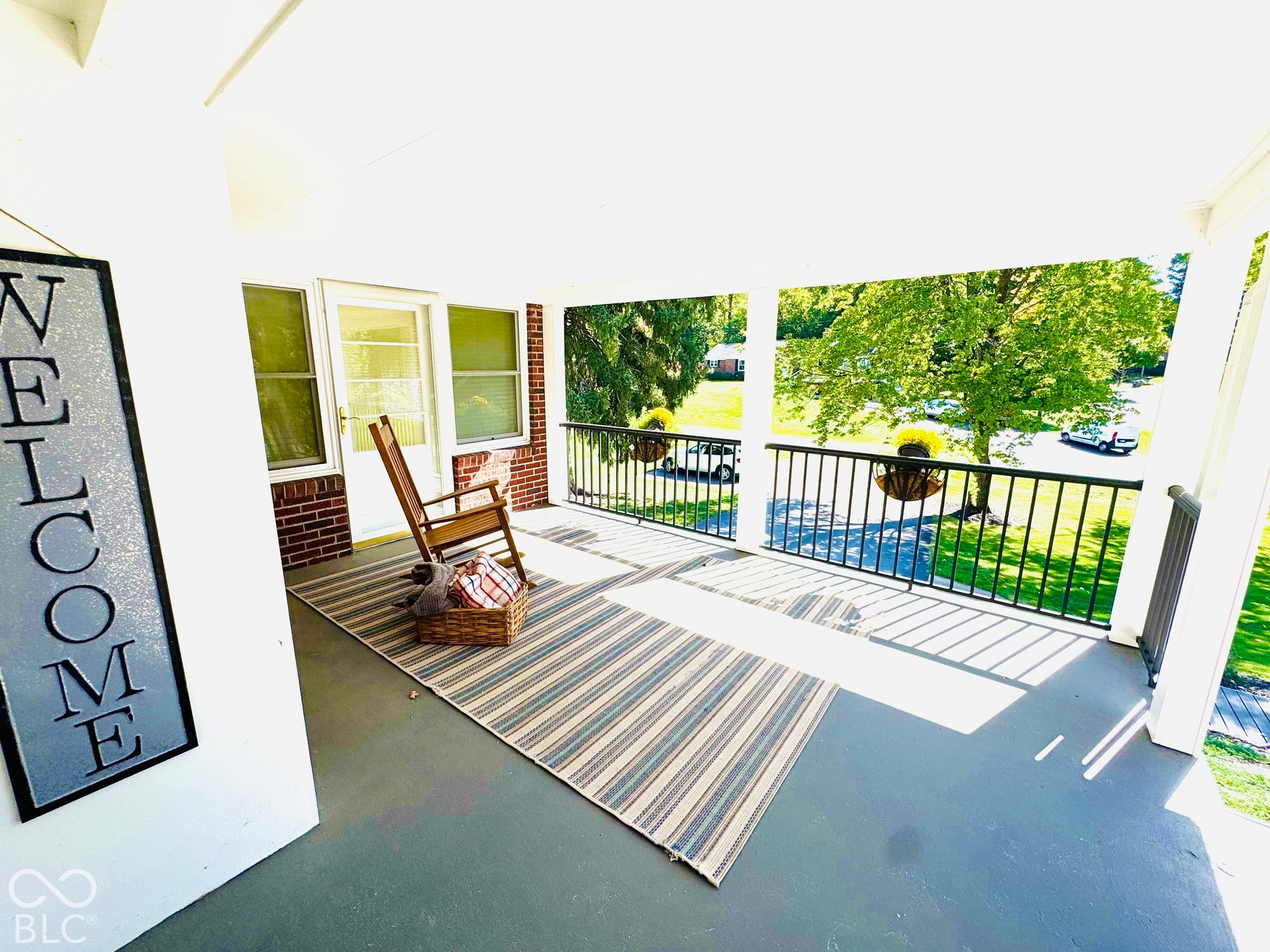 Covered front porch featuring white columns and black metal railings