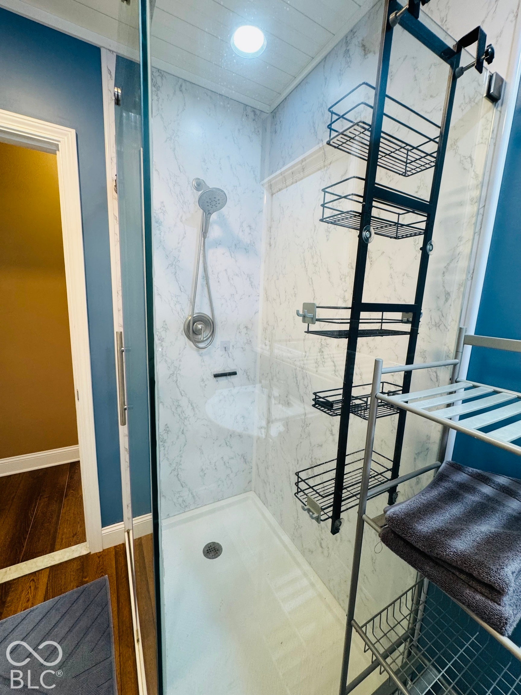 Glass-enclosed shower with a handheld showerhead and recessed lighting