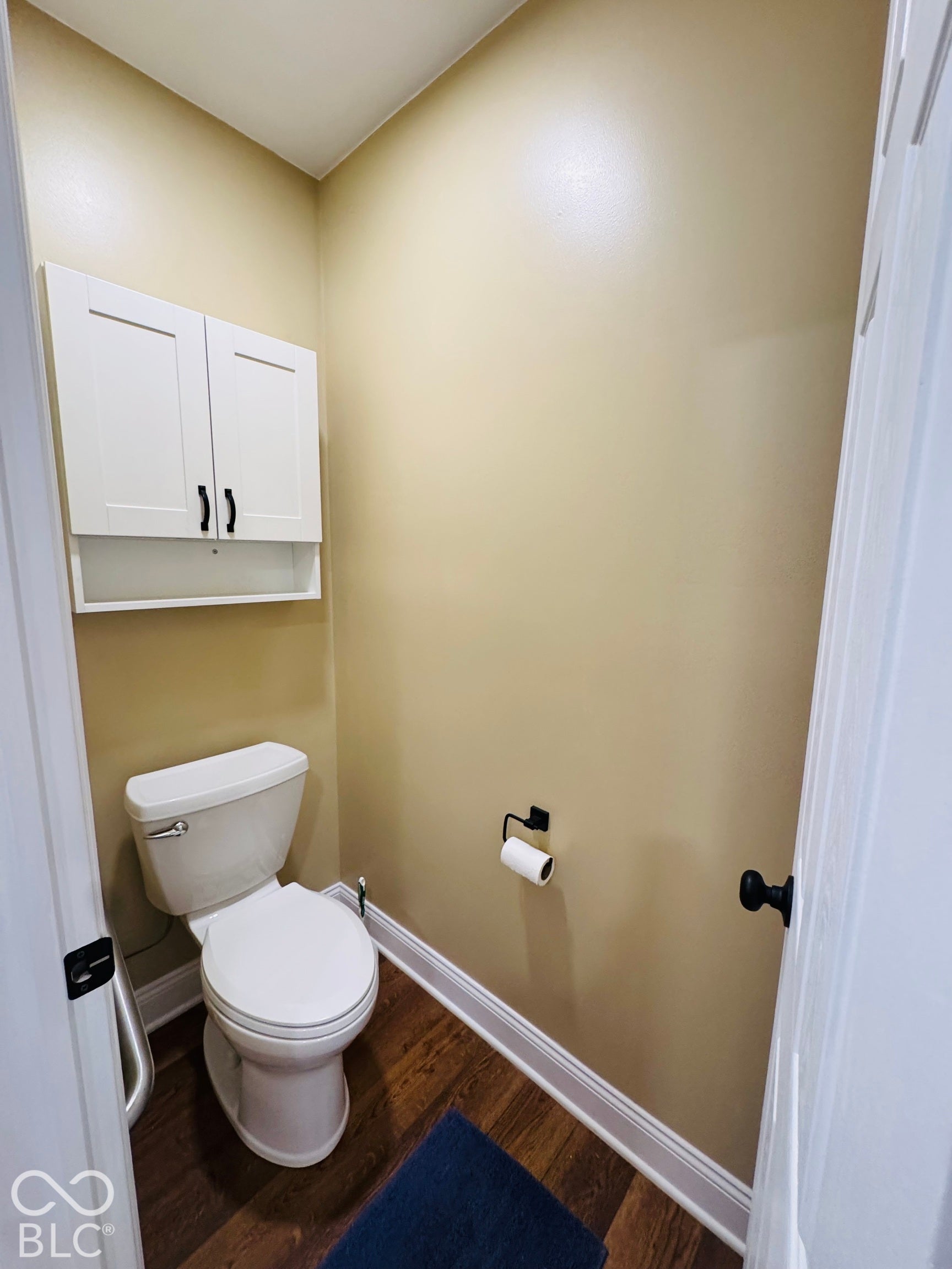 Water closet that includes White cabinetry with black hardware, wood-finish flooring