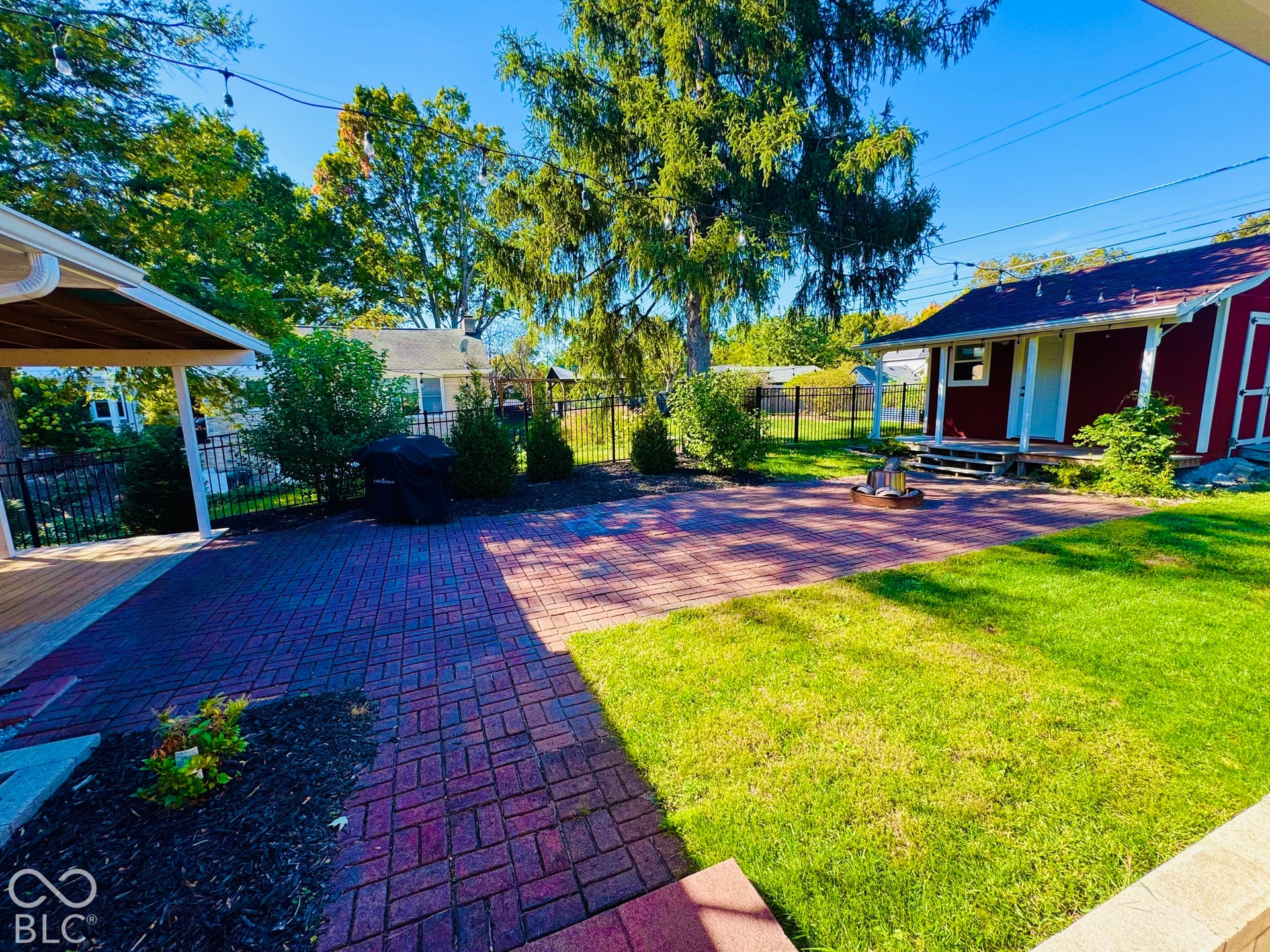 Expansive backyard featuring a brick paver patio, a covered patio area, and a grassy lawn