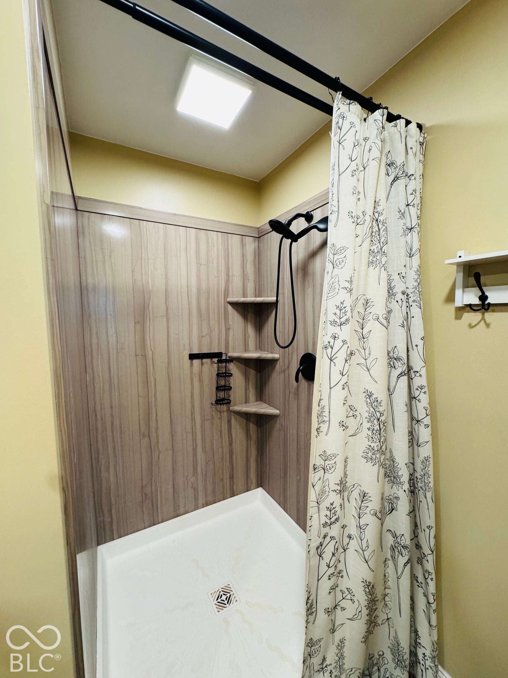 Huge Walk in Shower with wood-finish paneling, matte black fixtures, and built-in corner shelving