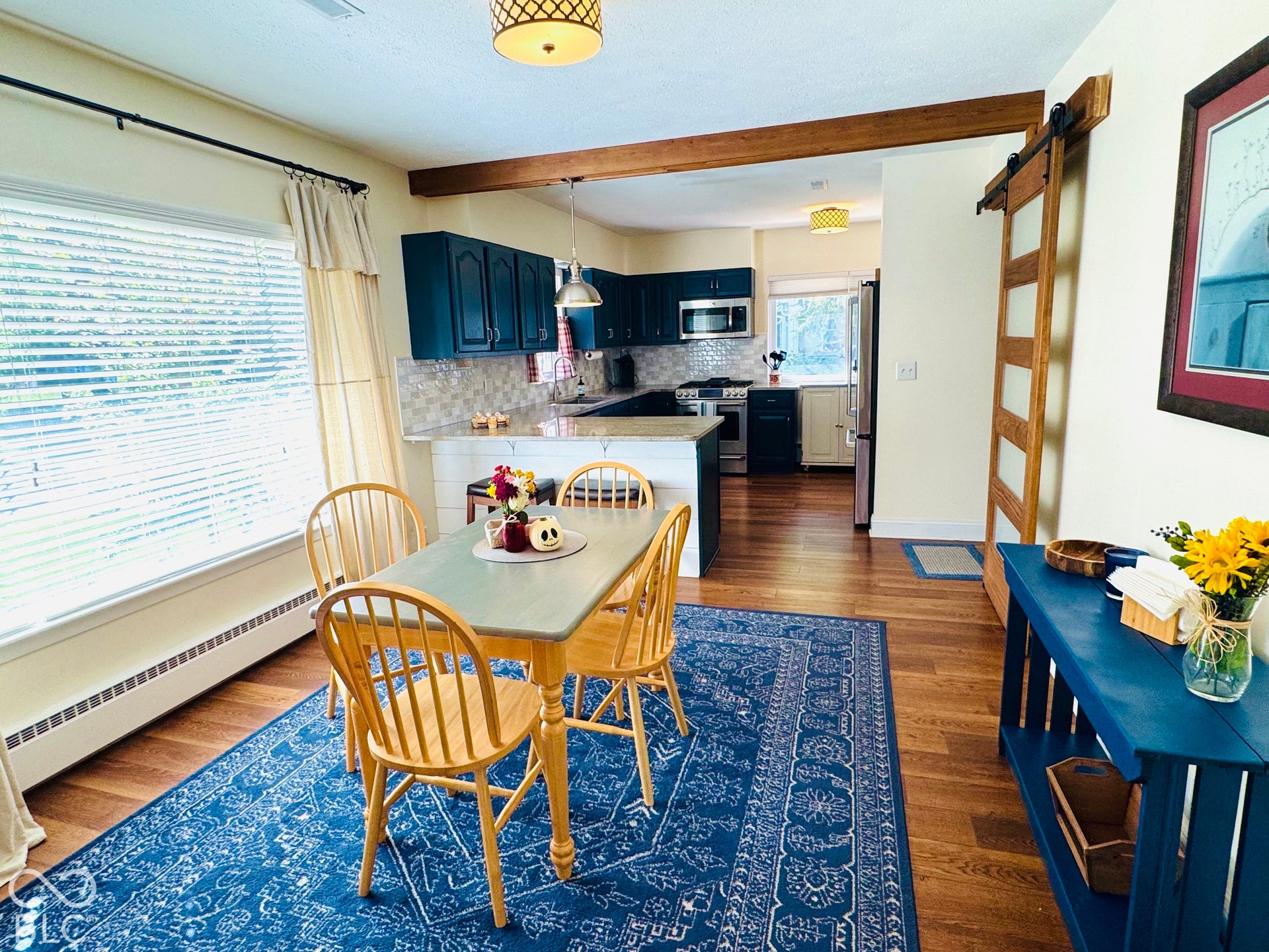 All updated kitchen with Wood-finish flooring throughout, featuring Granite counters!  dark blue cabinetry, a tile backsplash, and stainless steel appliances