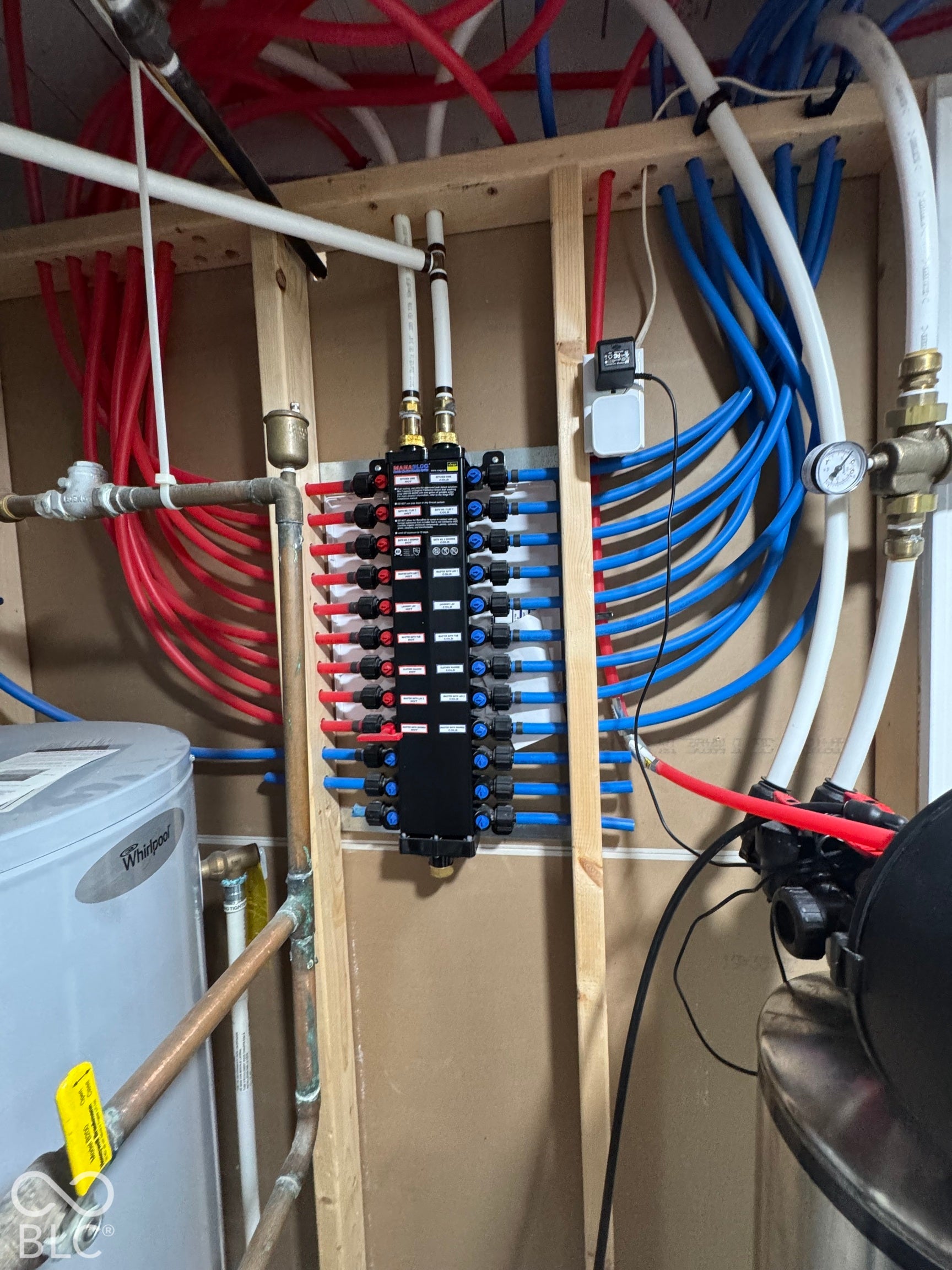 New Advanced plumbing manifold system with red and blue PEX tubing, copper piping, and a updated newer water heater