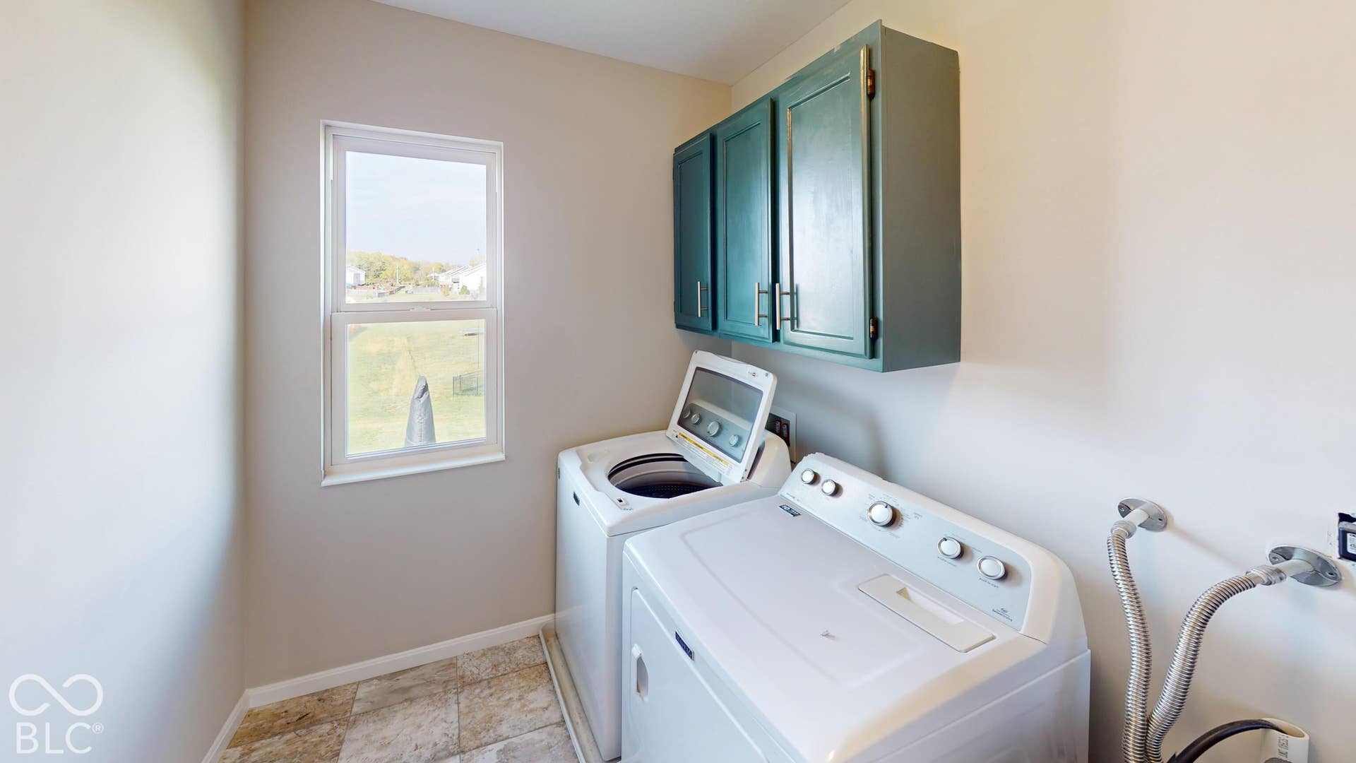 Wall-mounted cabinetry, single window, and tiled flooring