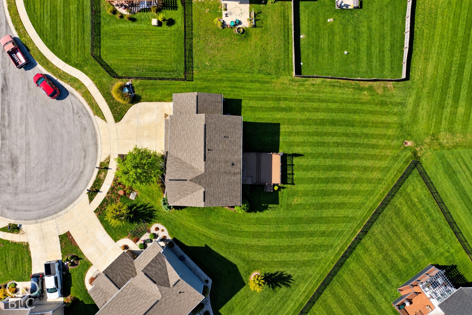 *AI - Color Enhancement* Expansive green lawn with defined property lines, attached rear deck, and a cul-de-sac street frontage