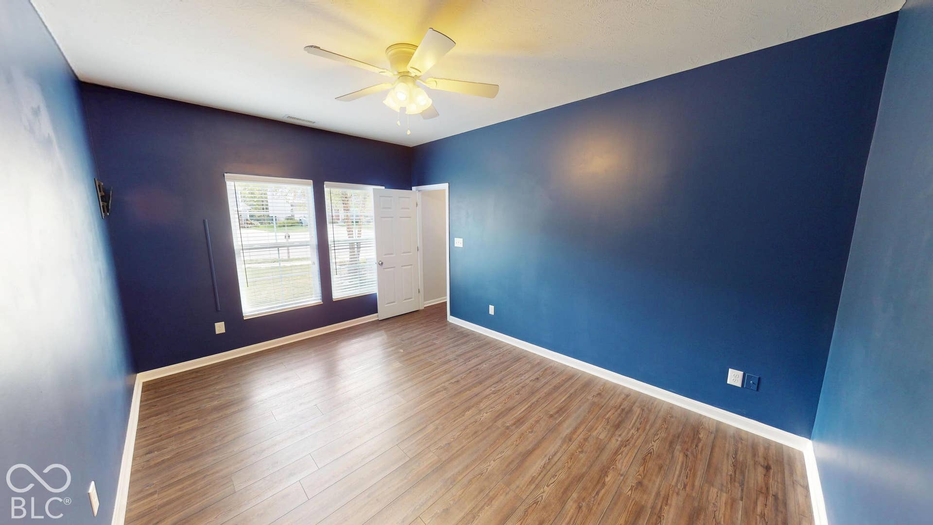 Wood-finish flooring with white trim, ceiling fan light fixture, and double windows with white blinds. Our seller's used it as a office