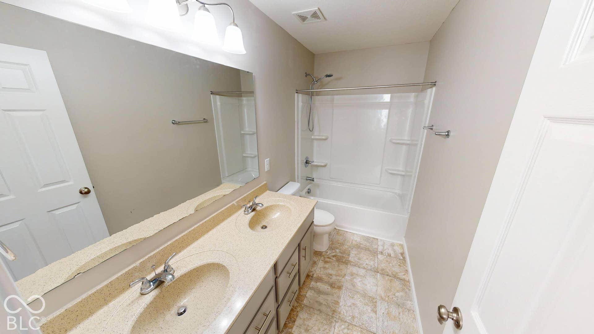 Dual vanity with integrated sinks, full-width mirror, light-toned wall paint, and a shower-over-tub combination