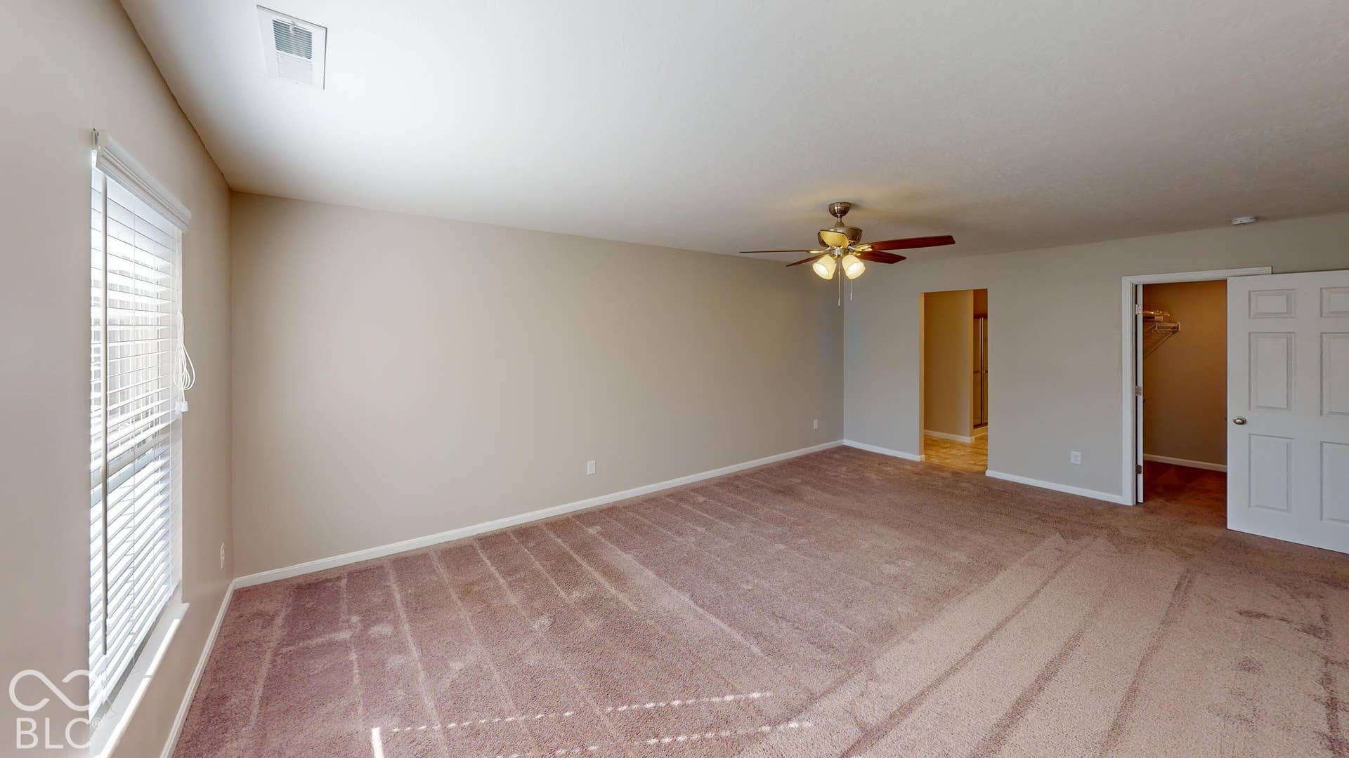 Bedroom #3 | Spacious room featuring neutral wall tones, textured carpeting, a window with blinds, and a ceiling fan with integrated lighting
