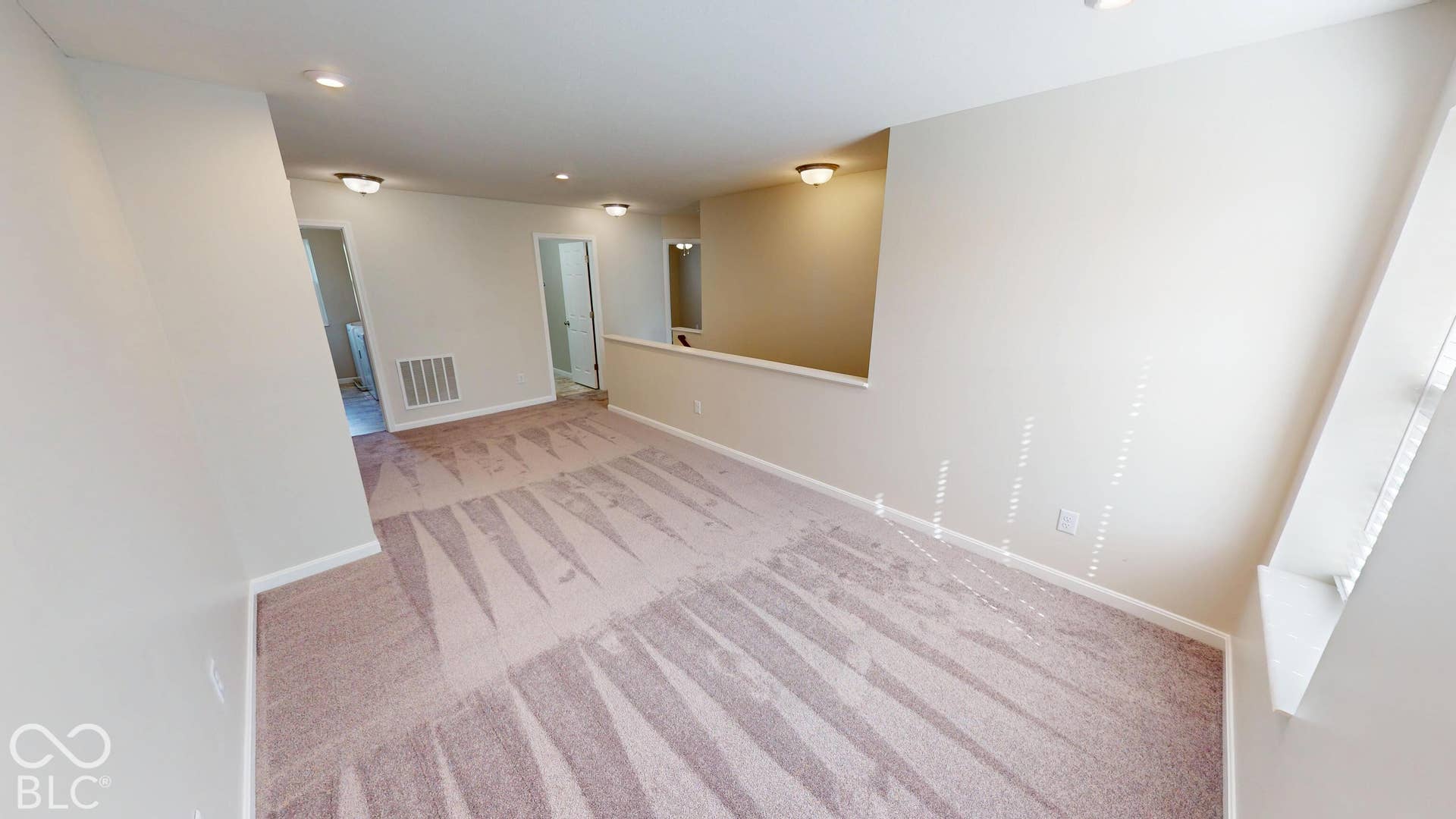 Expansive carpeted area with neutral wall finishes, recessed lighting, and natural light from a window