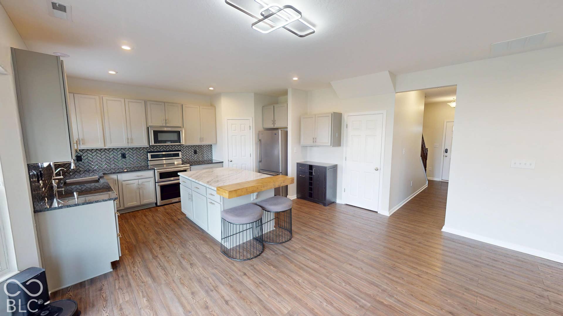 Kitchen featuring wood-finish flooring, recessed lighting, white cabinetry, dark stone countertops, and stainless steel appliances