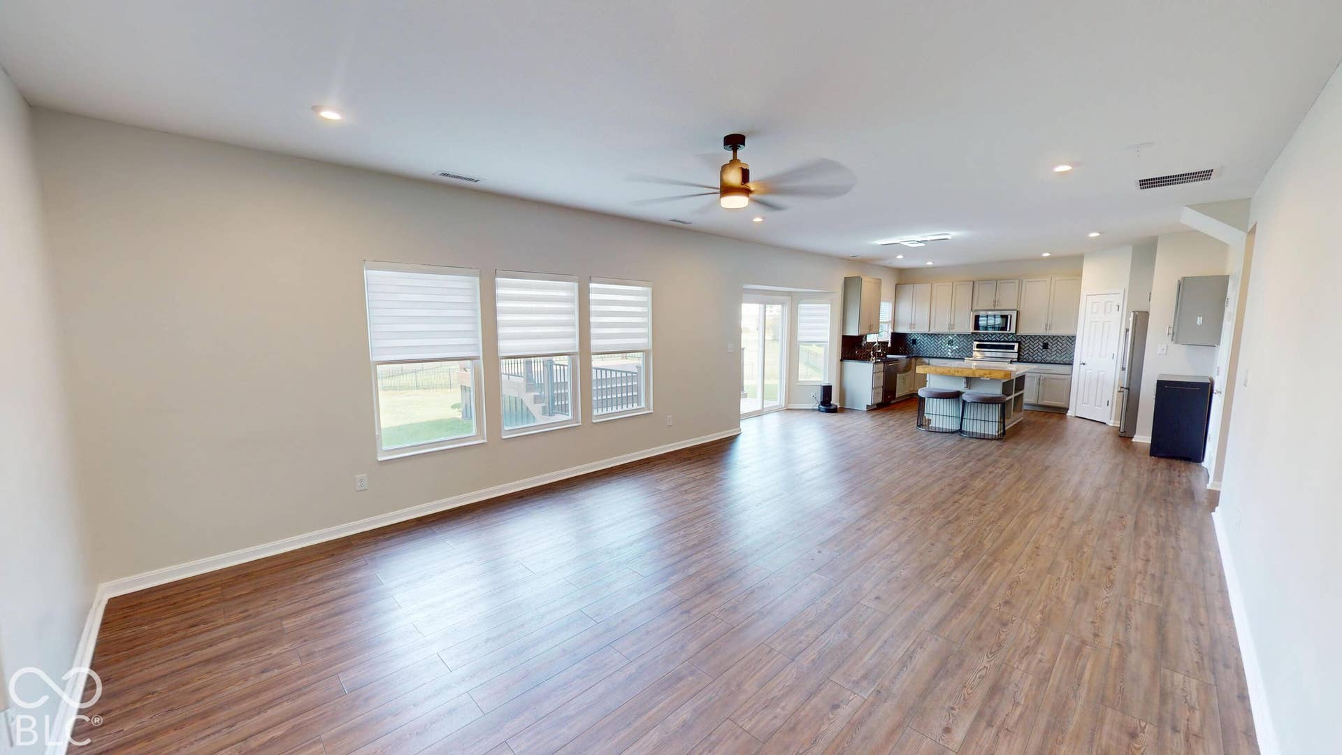 Expansive open-concept space featuring wood-finish flooring, recessed lighting, and a contemporary ceiling fan