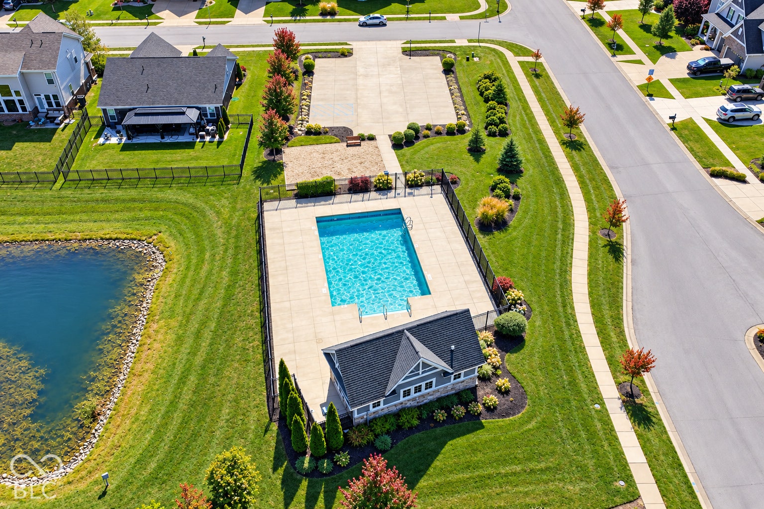 *AI - Color Enhancement* Community swimming pool with surrounding fencing, adjacent pool house, and nearby sand court