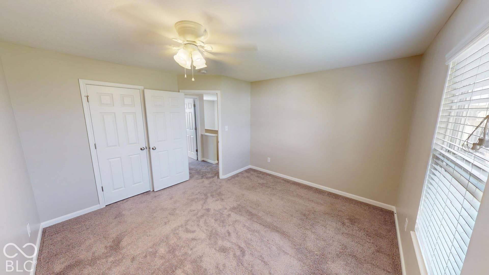 Bedroom #1 | Neutral wall paint, carpet flooring, window with blinds, and white panel doors