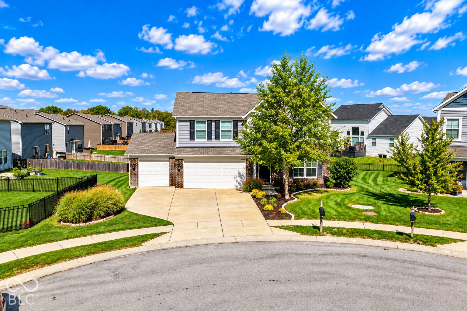 *AI - Color Enhancement* Two-story residence featuring light gray siding, brick accents, and a two-car garage with white doors