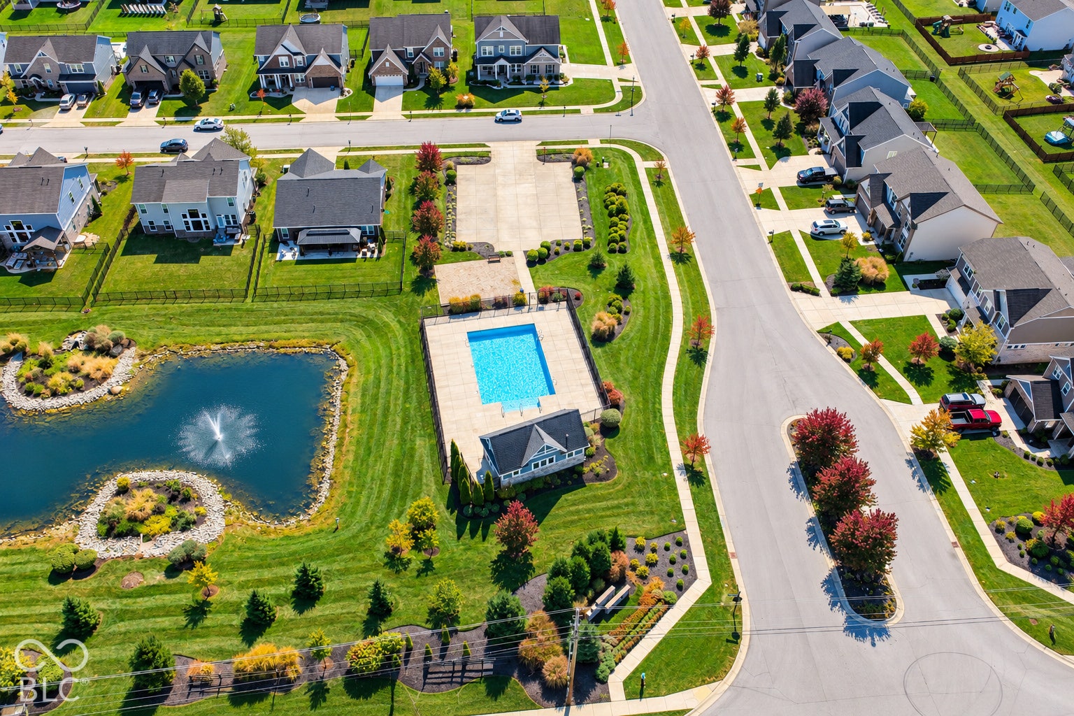 *AI - Color Enhancement* Community swimming pool, paved pool deck, ornamental pond with fountain, landscaped common areas, and curvilinear street design