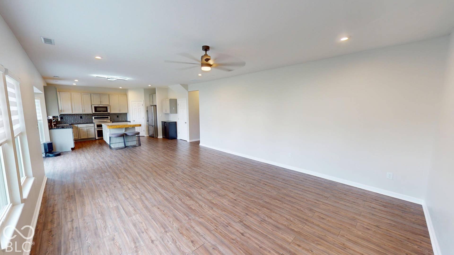 Open-concept living area with wood-finish flooring, recessed lighting, and a ceiling fan
