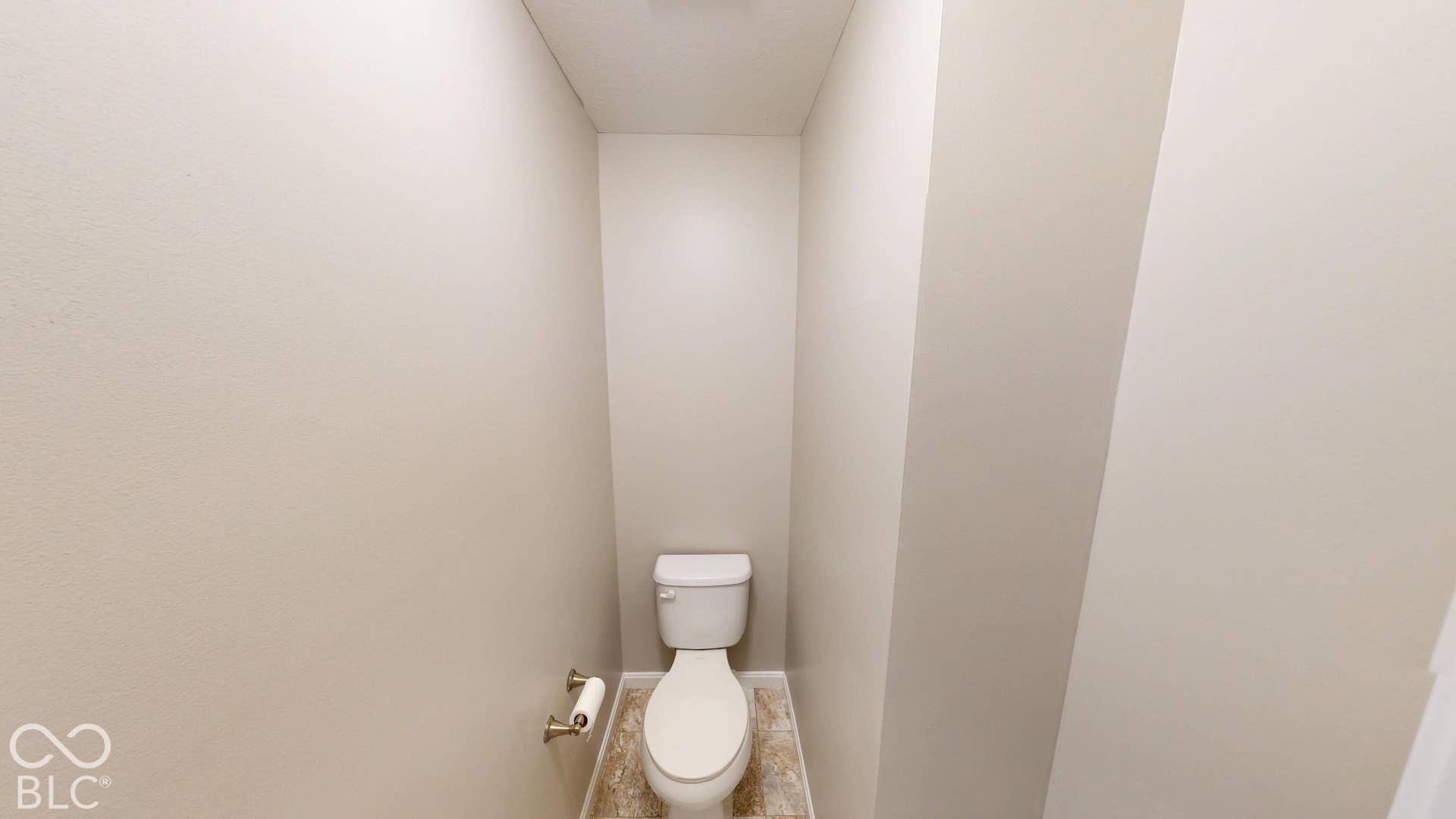 White toilet with a chrome toilet paper holder and patterned floor tiling