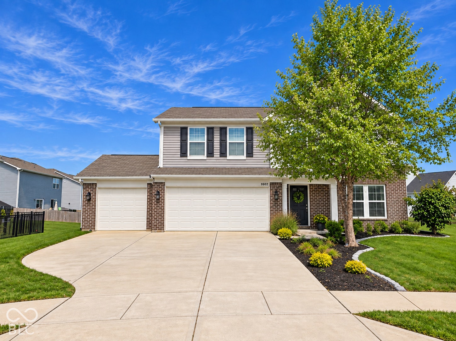 *Color Enhancement* Two-story residence featuring a brick and siding exterior, a three-car garage, and a concrete driveway