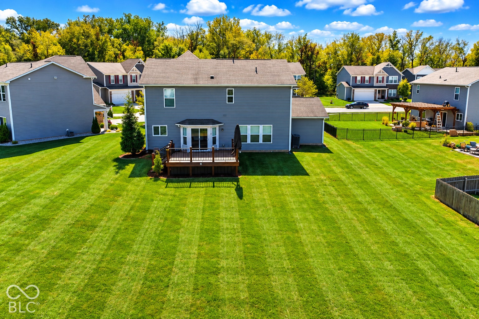*AI - Color Enhancement* Expansive green lawn with a wooden deck featuring white railings