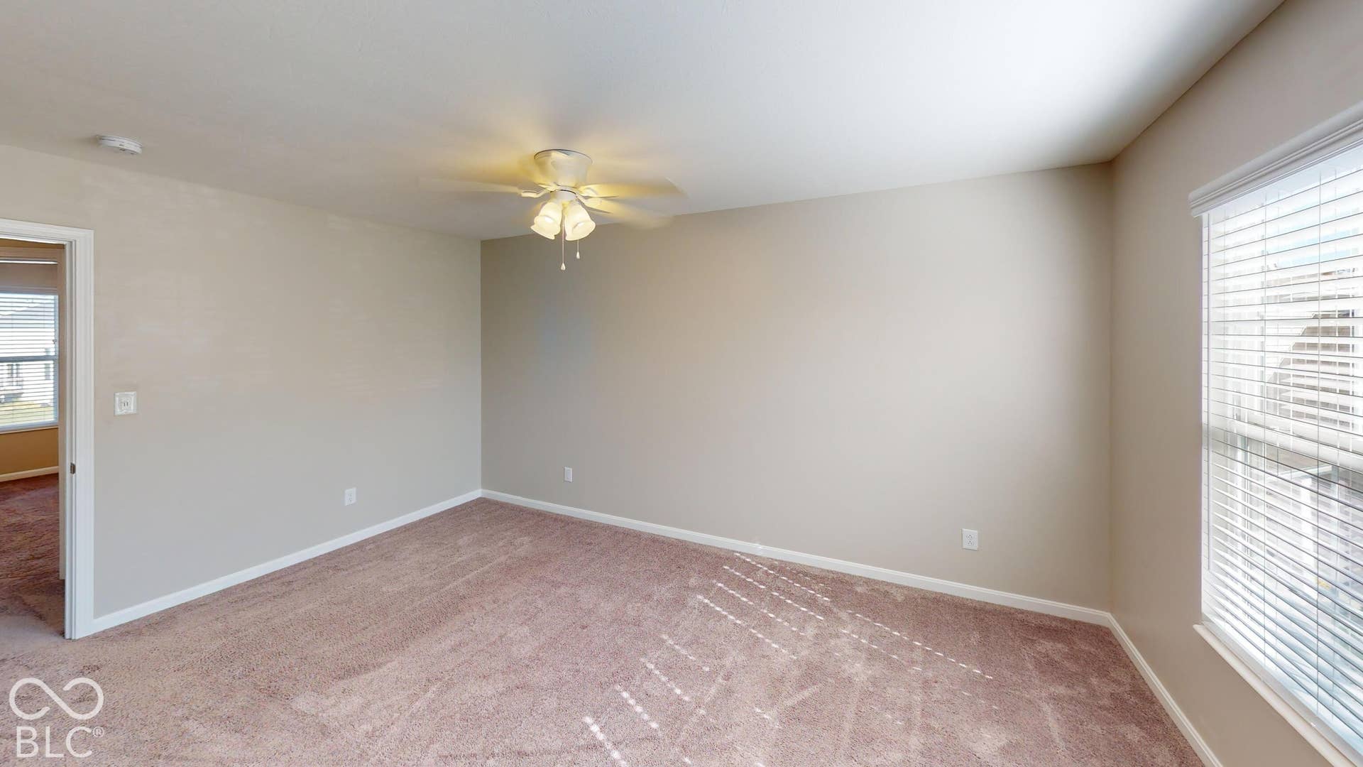 Bedroom #2 | Neutral tone wall paint, textured carpet flooring, window with blinds, and ceiling fan with integrated lighting