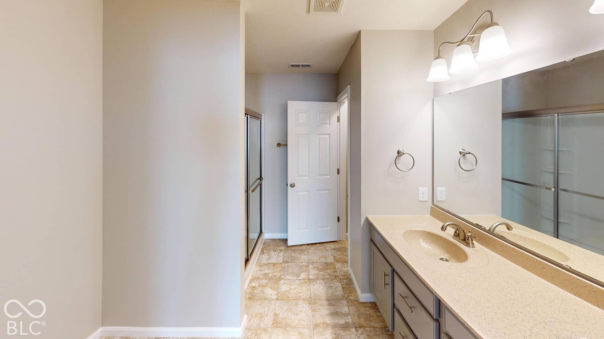 Double vanity with integrated sinks, brushed nickel fixtures, wall-mounted mirror, and overhead lighting