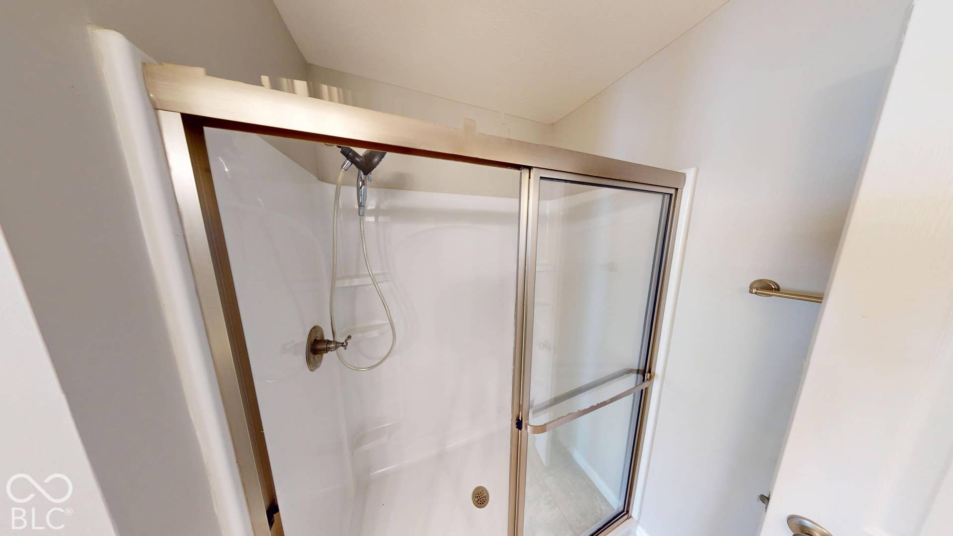 Shower enclosure with a white acrylic base and walls, brushed nickel frame, and a bronze shower head