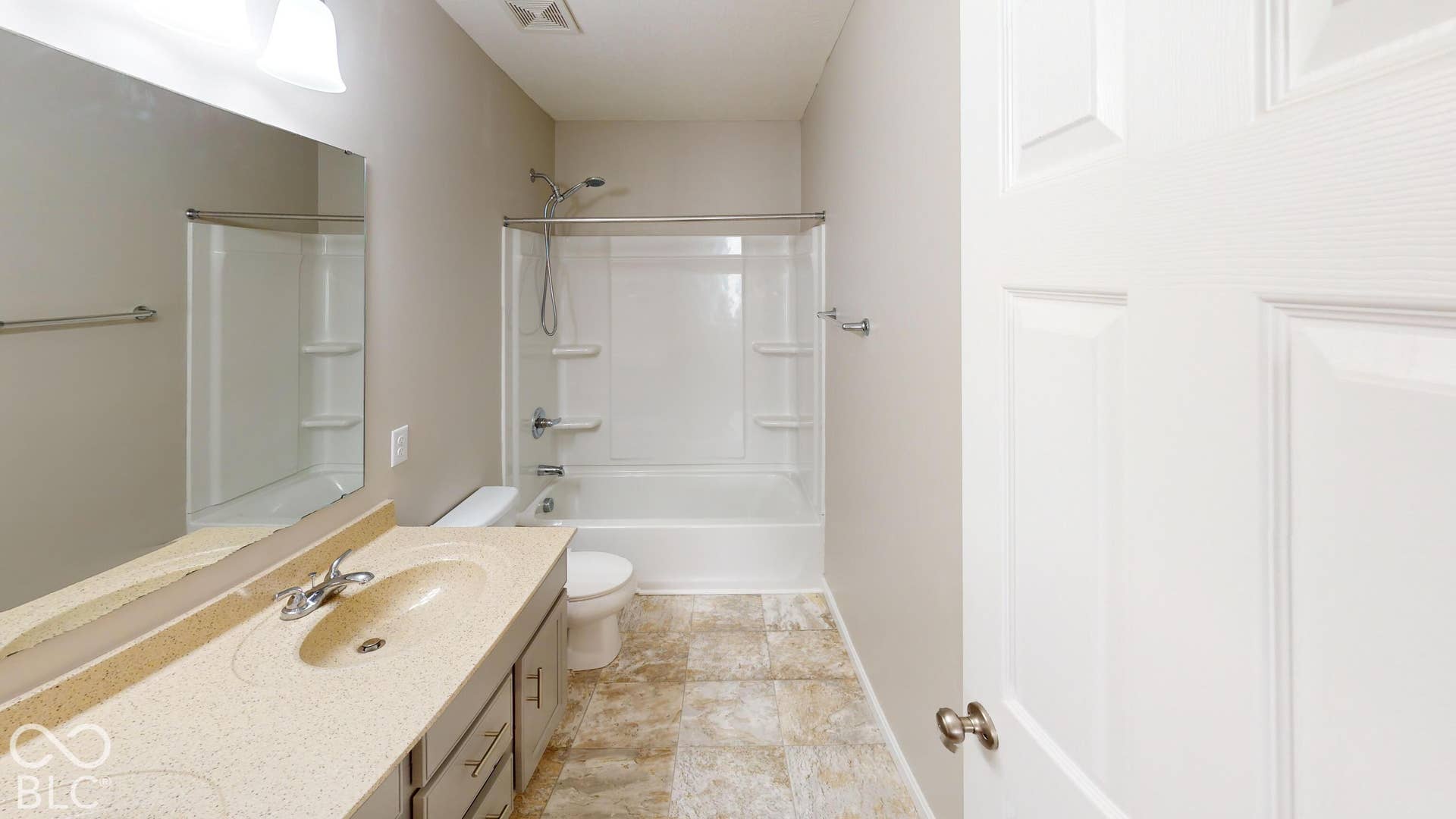 Bathroom featuring a vanity with an integrated sink, a rectangular mirror, a shower-tub combination, and tiled flooring