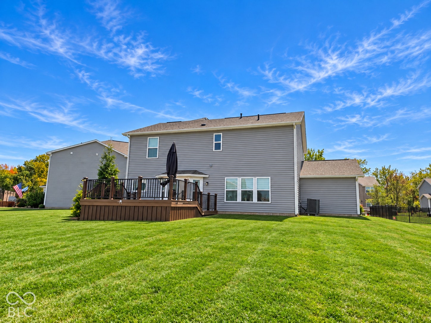 *AI - Color Enhancement* Expansive lawn with a multi-level composite deck, black railings, and a walk-out door