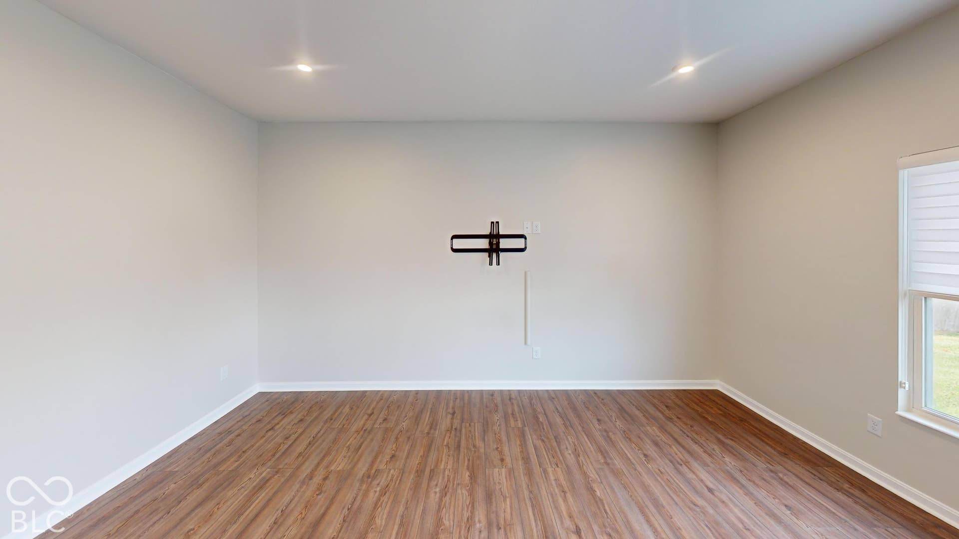 Wood-finish flooring, recessed ceiling lights, and a wall-mounted bracket
