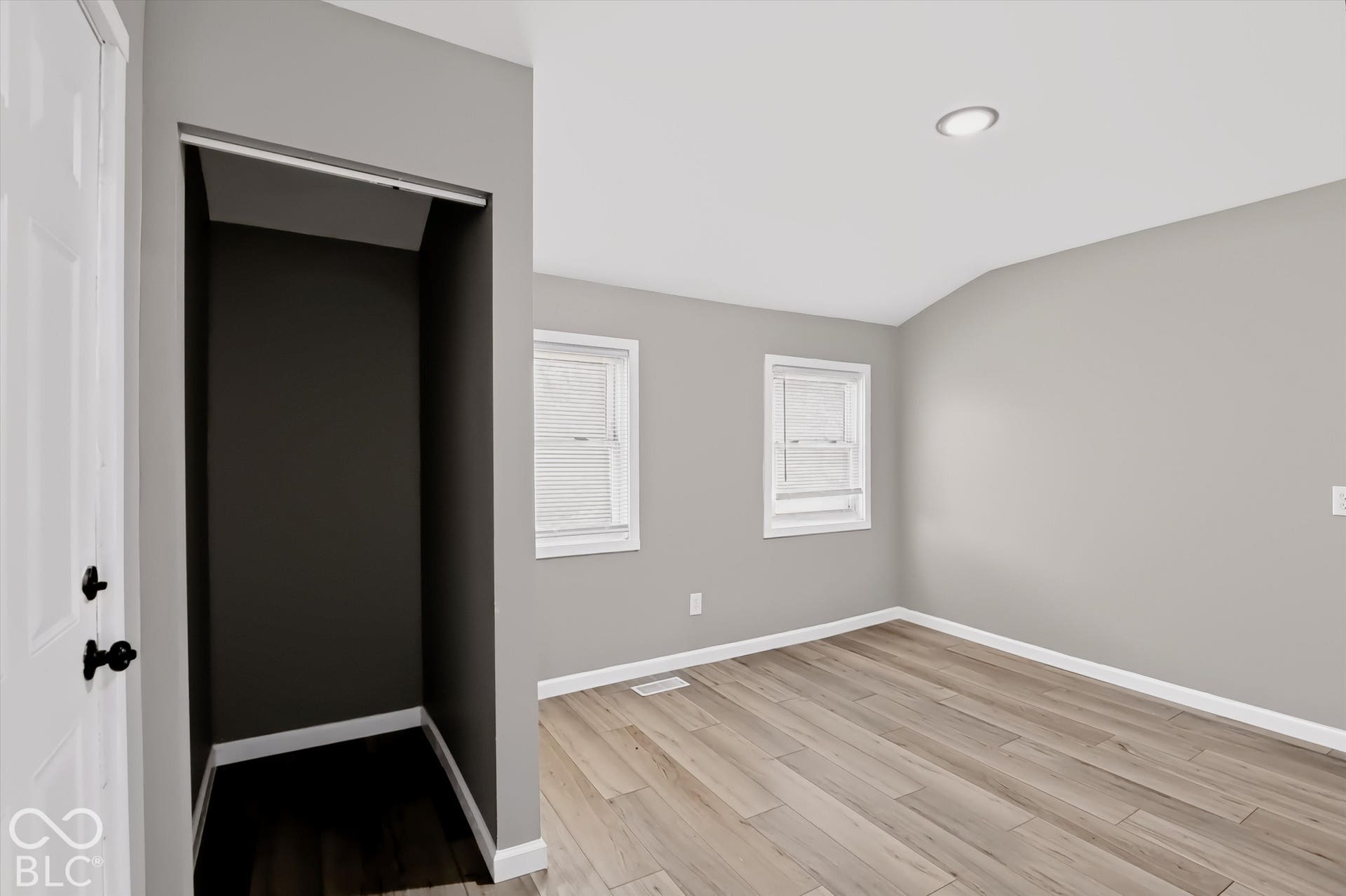 Room with wood-finish flooring, recessed lighting, vaulted ceiling, and dual windows