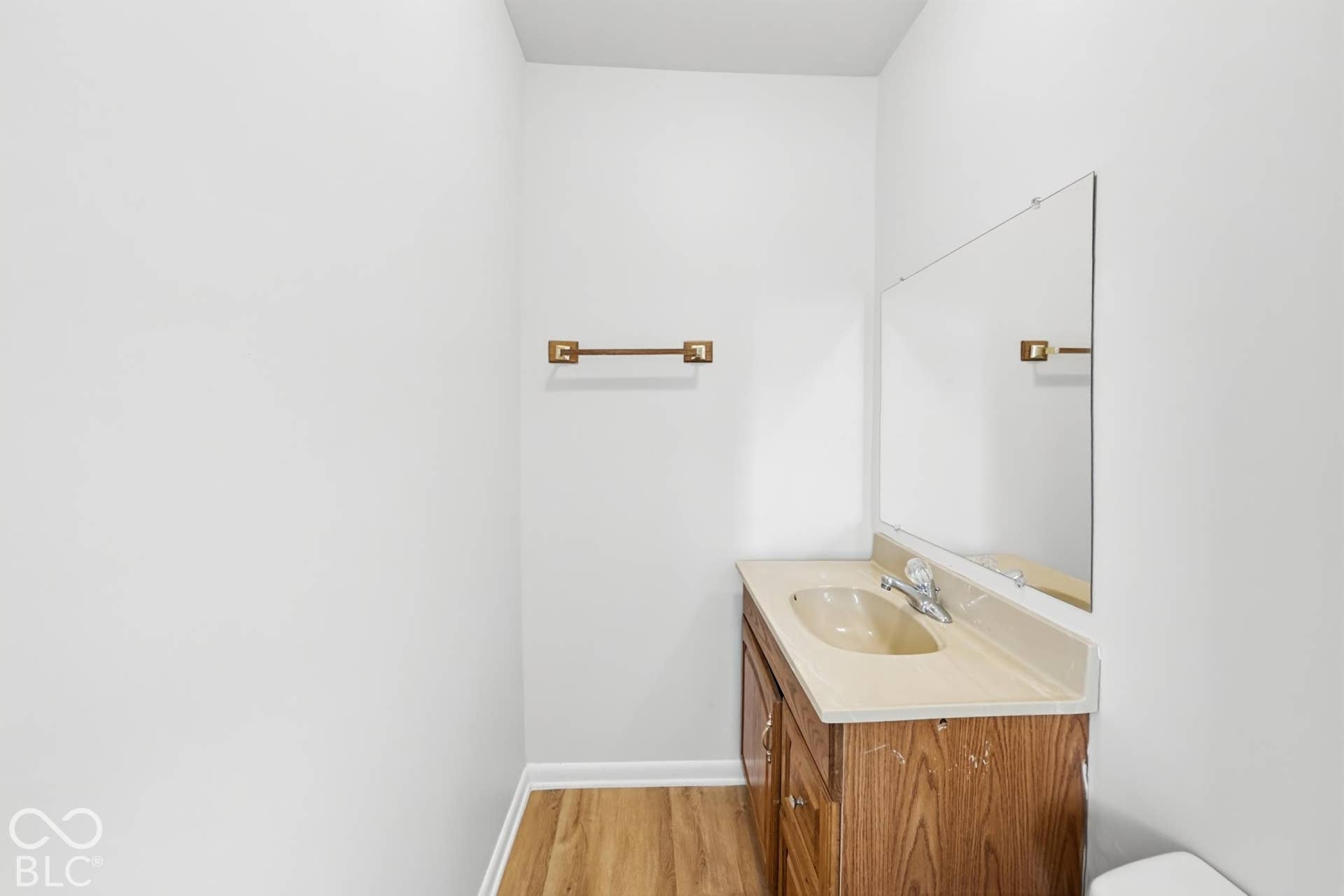 Vanity with integrated sink, wall-mounted mirror, and wood-finish flooring