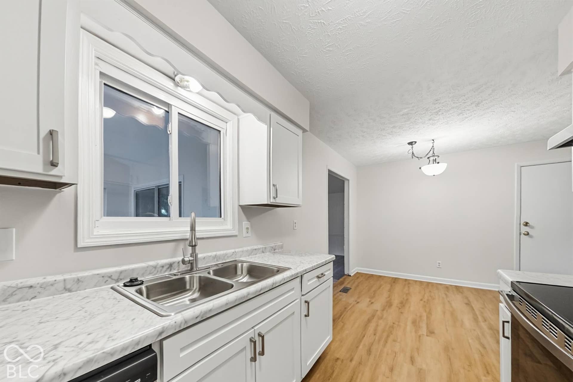 Kitchen featuring a dual basin sink with a brushed nickel faucet, white cabinetry, and light-toned countertops