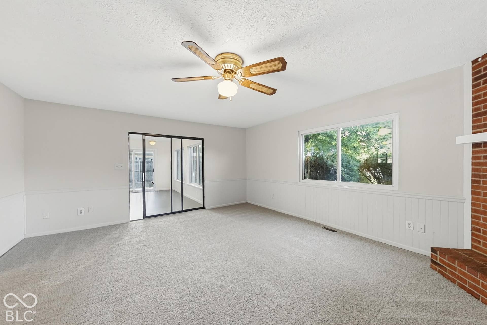 Light gray carpeted flooring, white wainscoting, and a brick fireplace