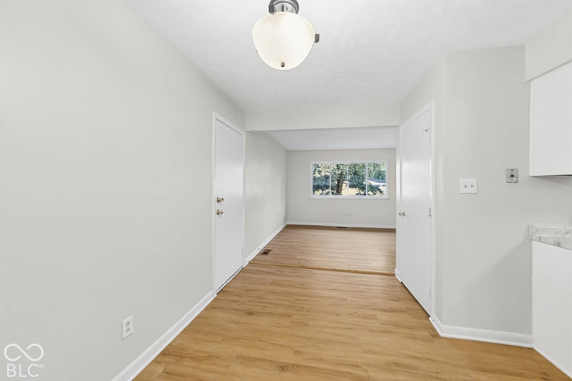 Wood-finish flooring throughout, complemented by a large window and neutral wall tones