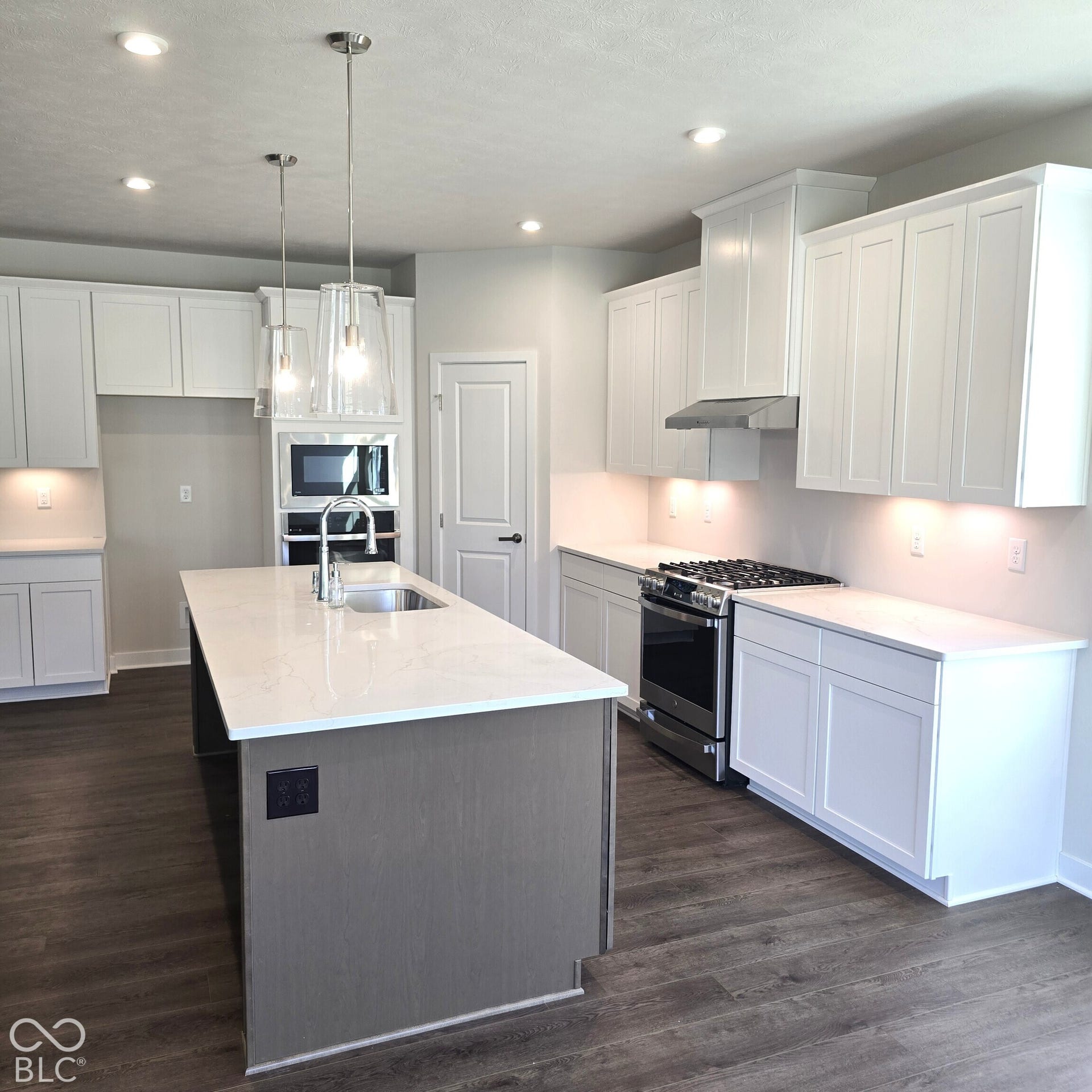 Kitchen featuring a central island with a sink, white cabinetry, integrated stainless steel appliances, wood-finish flooring, and recessed lighting