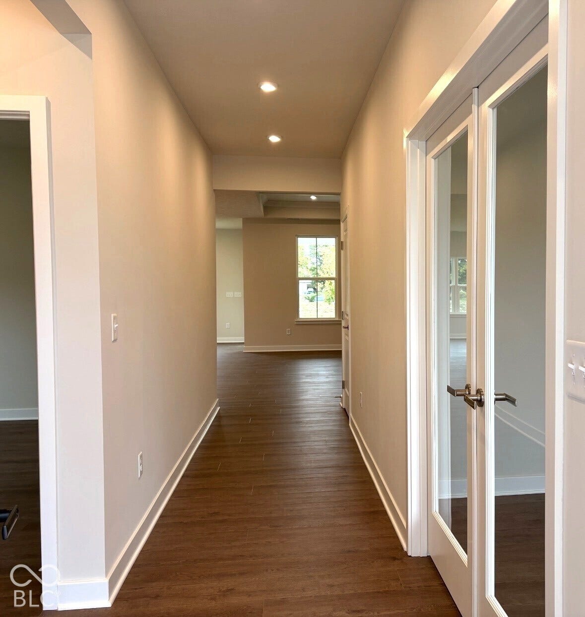 Hallway featuring wood-finish flooring, recessed lighting, and a glass-paneled door