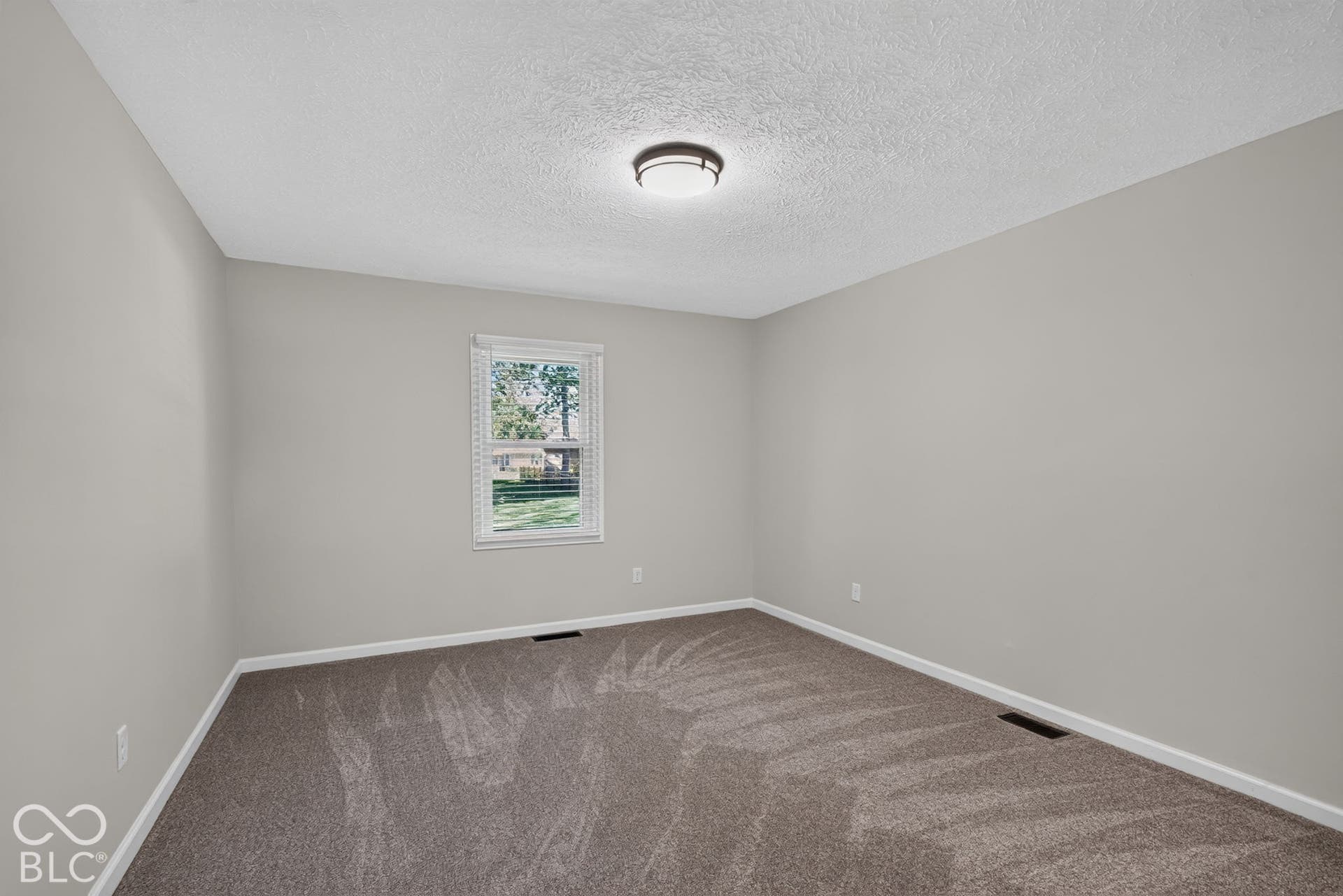 Neutral-toned walls complement the textured carpet flooring