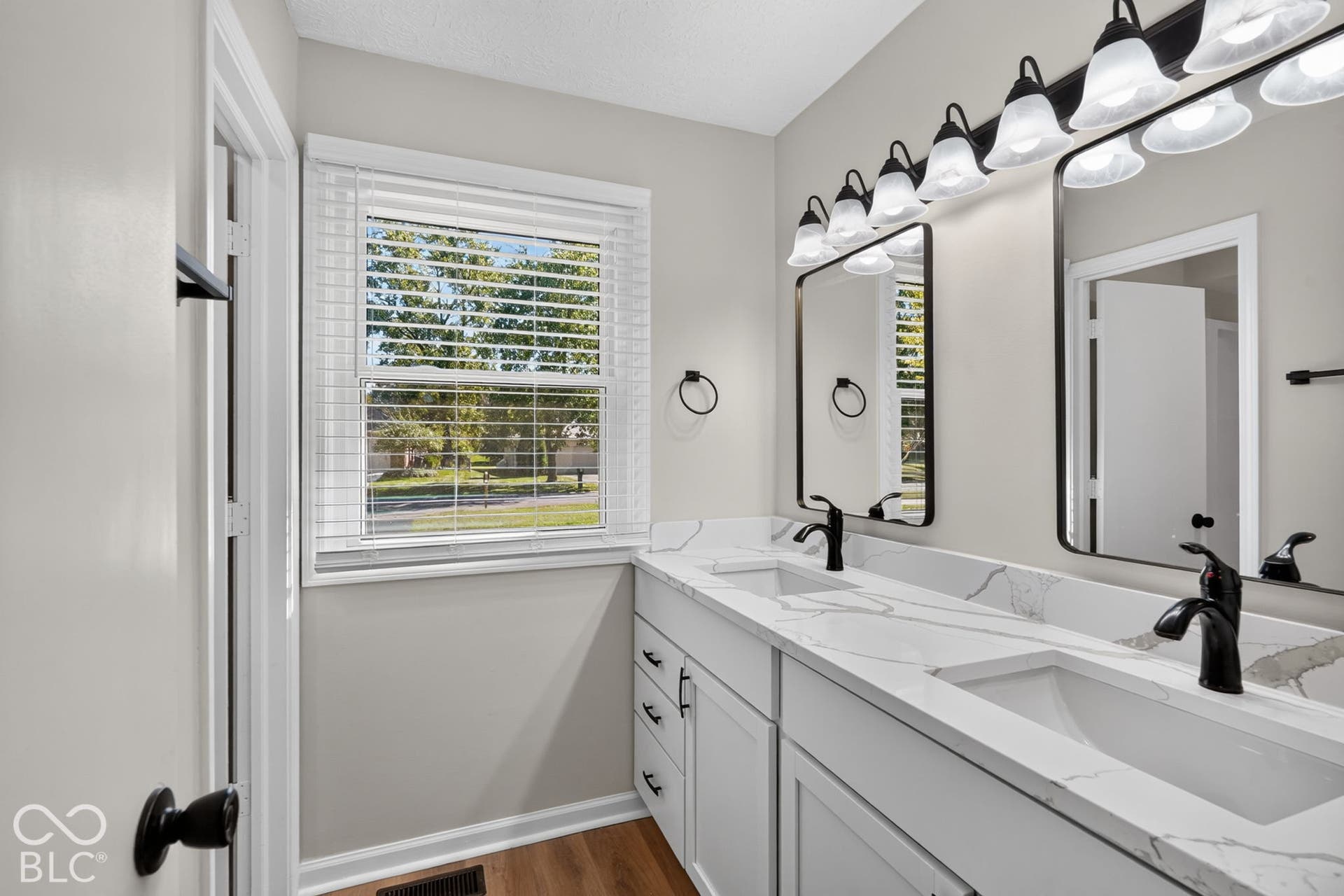 Dual vanity featuring integrated sinks, matte black fixtures, framed mirrors, and a multi-bulb light fixture