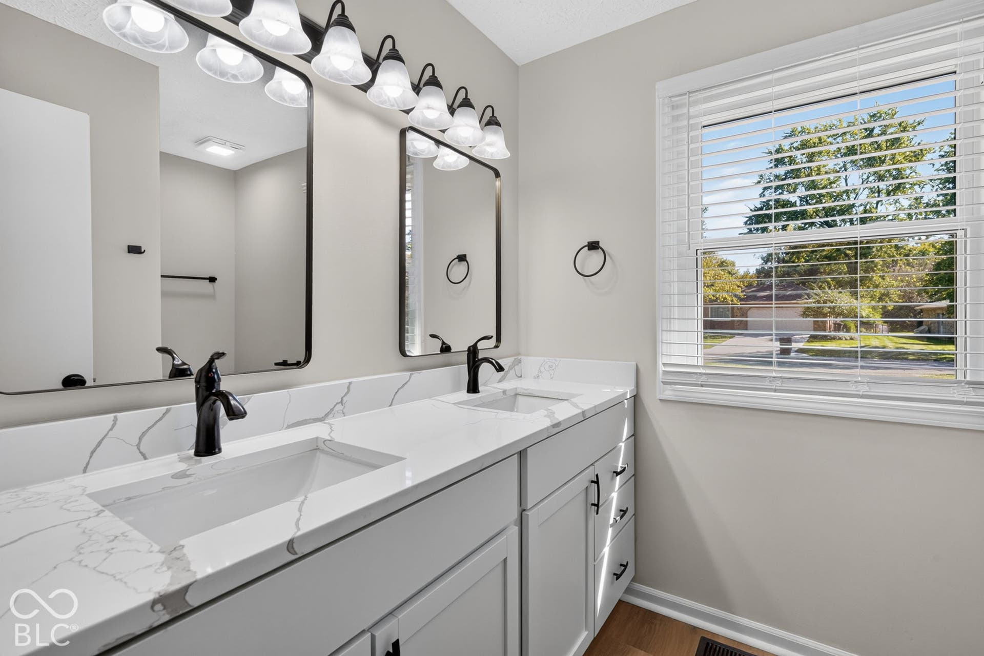 Dual vanity with integrated sinks, white quartz-finish countertop, matte black fixtures, and framed mirrors