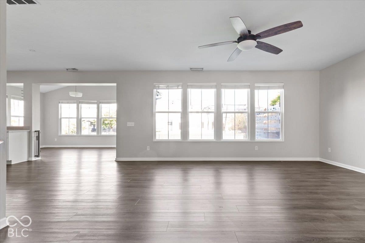 5570 W Stream Drive, McCordsville, IN 46055 Spacious interior with wood-finish flooring, a contemporary ceiling fan, and multiple windows providing natural light