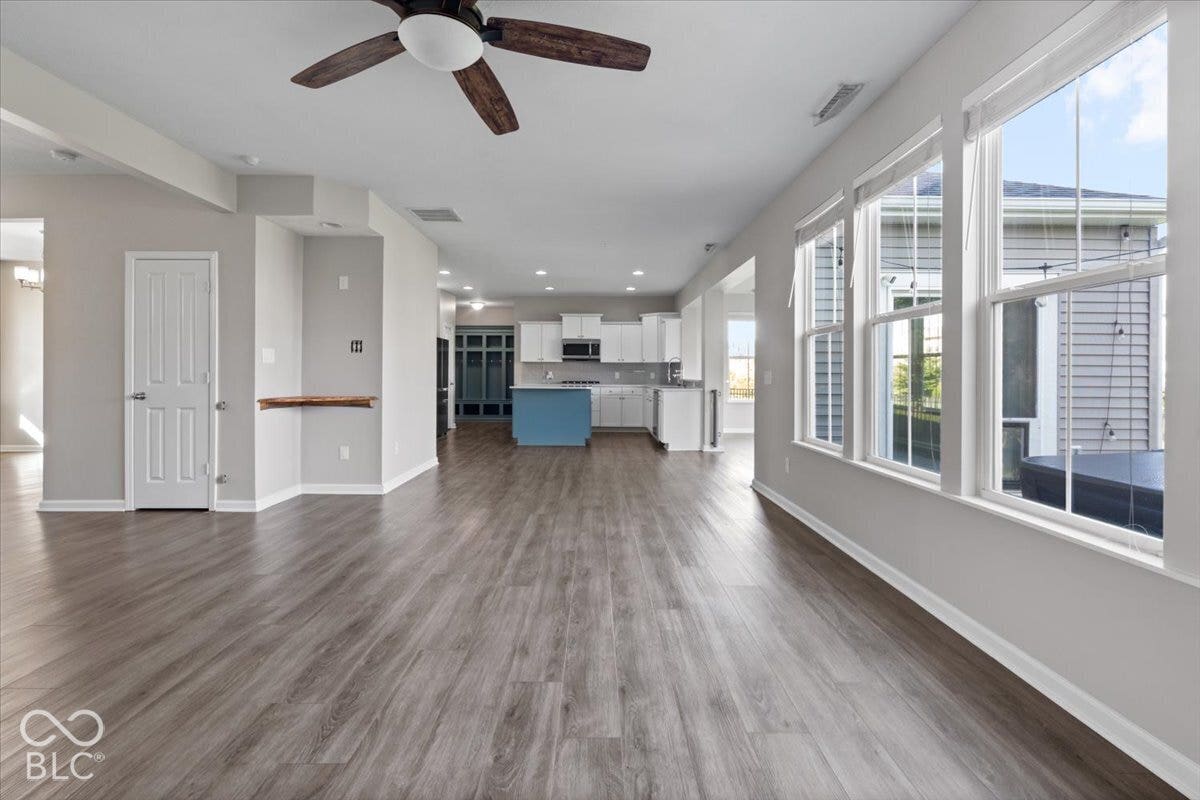 5570 W Stream Drive, McCordsville, IN 46055 Expansive open-concept interior featuring wood-finish flooring, a contemporary ceiling fan, and multiple windows