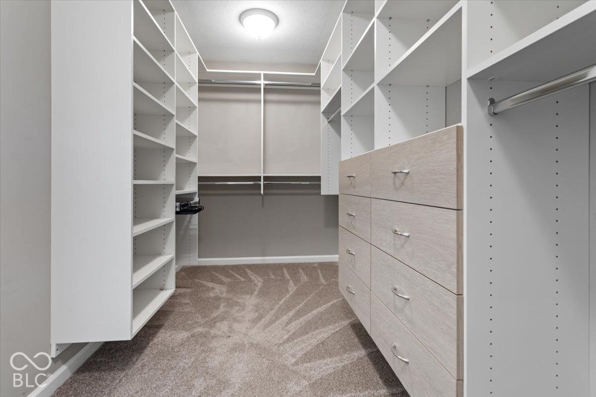 5570 W Stream Drive, McCordsville, IN 46055 Custom closet system featuring extensive shelving, built-in dresser with light wood-finish drawers, hanging rods, and recessed ceiling lighting