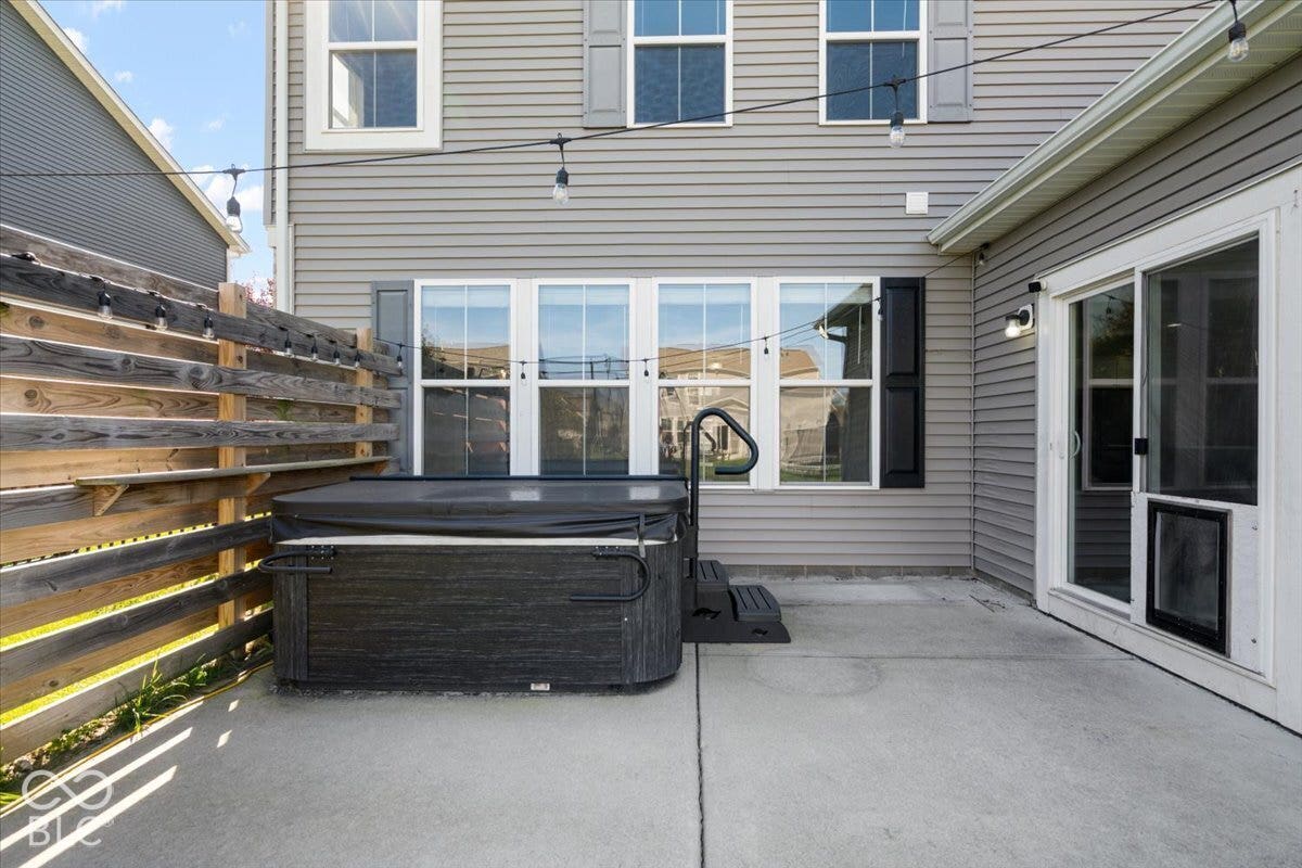 5570 W Stream Drive, McCordsville, IN 46055 Patio area featuring a built-in hot tub, privacy fence, and sliding glass door
