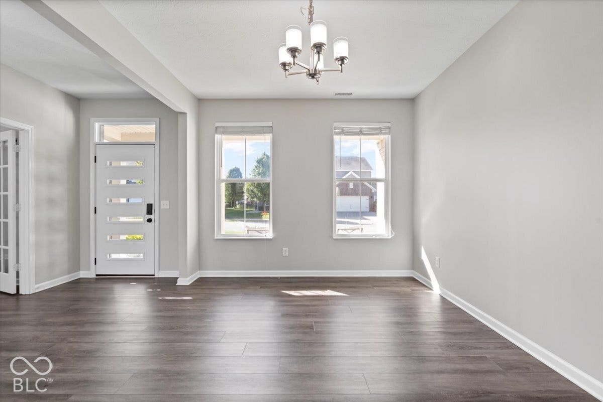 5570 W Stream Drive, McCordsville, IN 46055 Wood-finish flooring, modern chandelier, recessed lighting, white trim, and a contemporary front door with horizontal glass panels