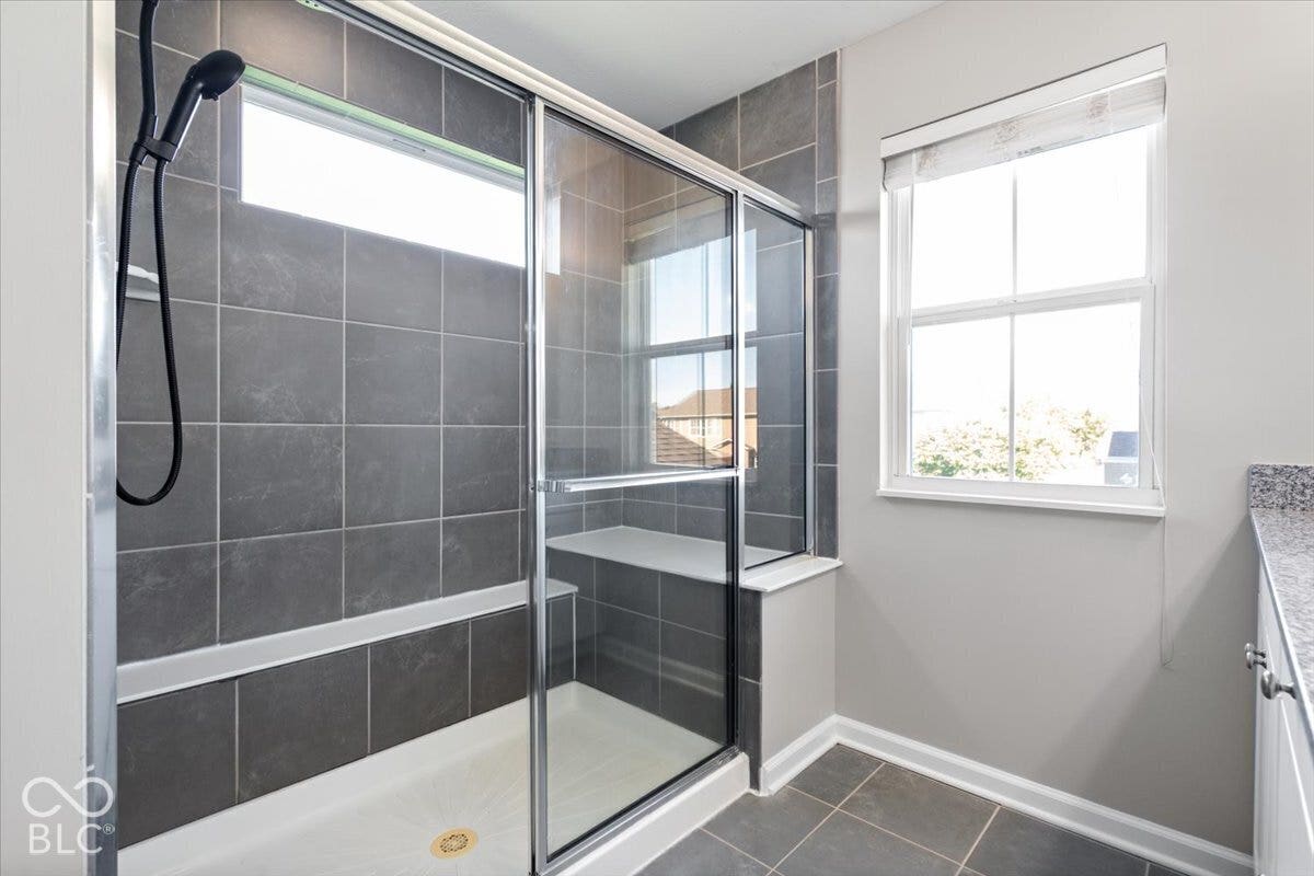 5570 W Stream Drive, McCordsville, IN 46055 Glass-enclosed shower with dark gray tile surround and built-in bench